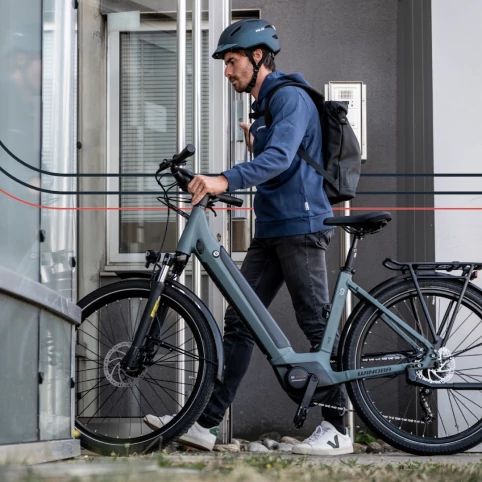 Un homme qui rentre dans un bâtiment avec son vélo