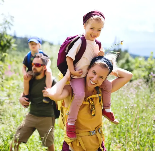 Une femme et un homme dans un champ qui portent leurs enfants sur leurs épaules